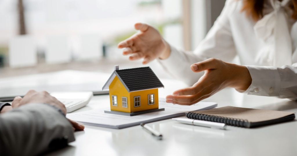 Home insurance Mesa AZ agent explaining coverage beside a model house